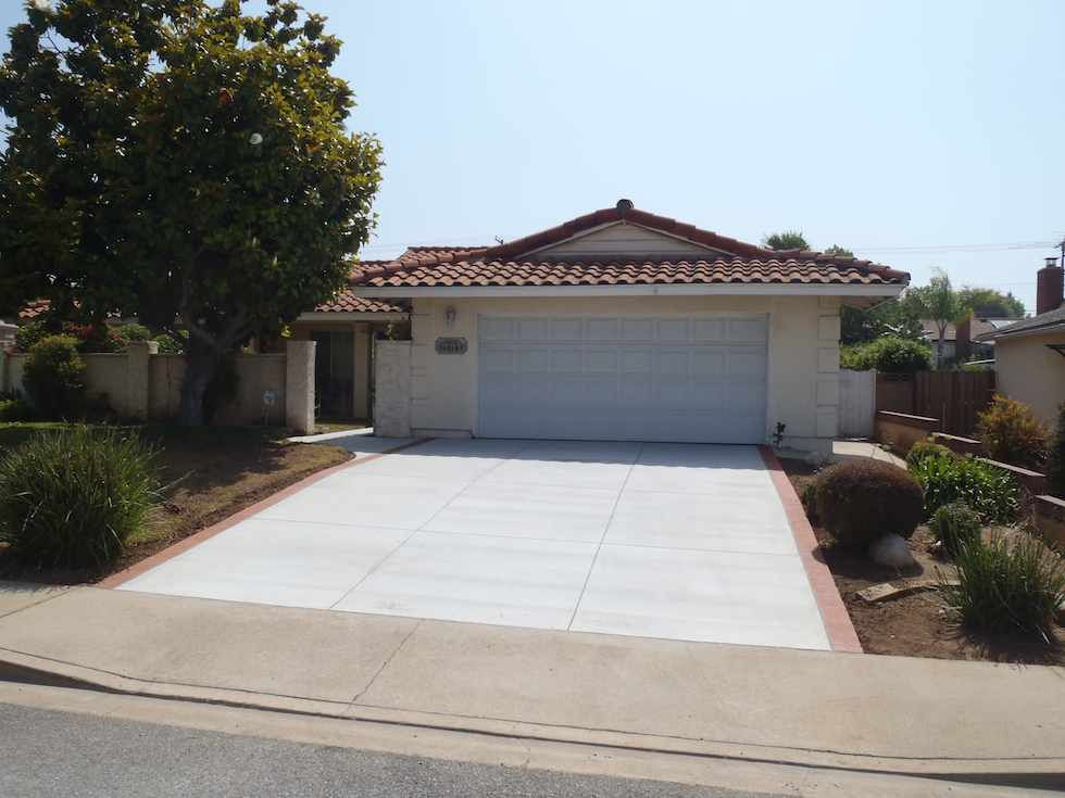 Finished concrete driveway with brick edges in front of a home, built by Driveway Masters