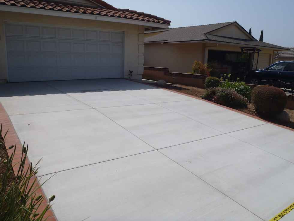 Fresh concrete driveway with brick ribbon edges, built by Driveway Masters